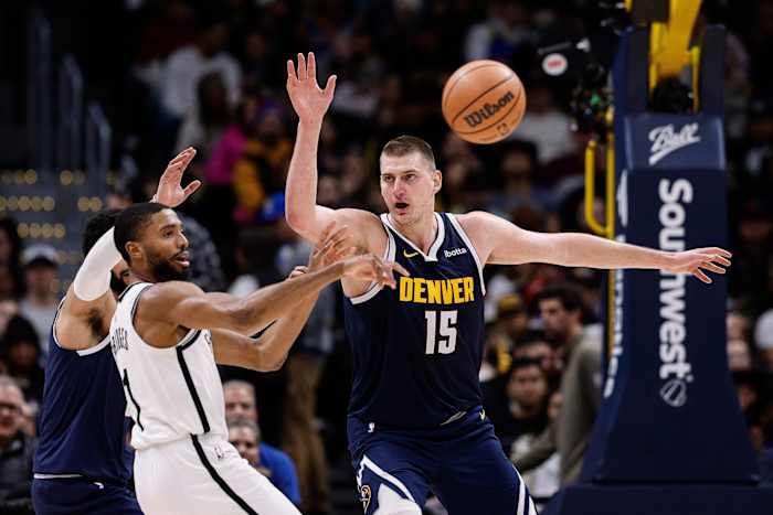 Brooklyn Nets forward Mikal Bridges (1) passes the ball under pressure from Denver Nuggets center Nikola Jokic (15)